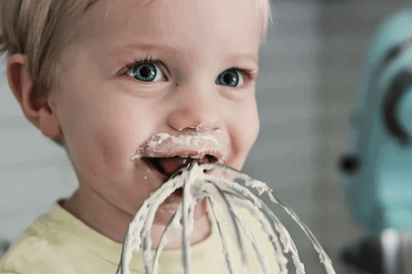 little boy licking a whisk