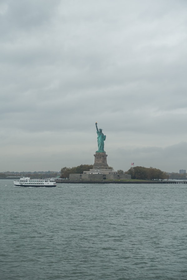 A large ship in a body of water with the statue of liberty