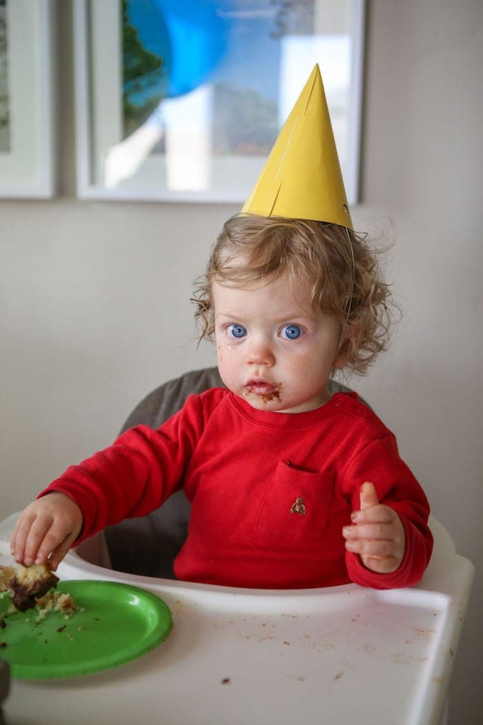 Eddie in a high chair eating cake
