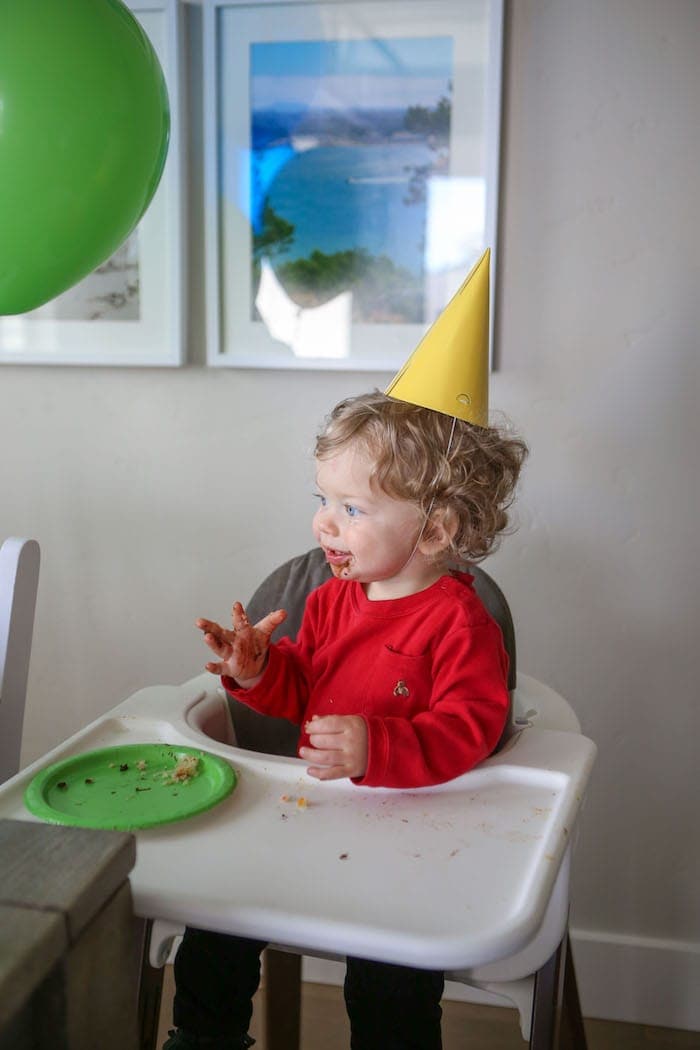 Eddie in a high chair eating cake