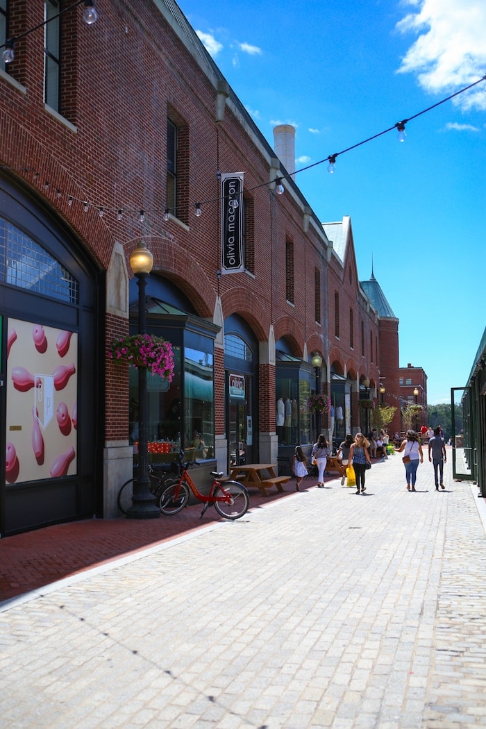 A group of people walking down a street next to a brick building