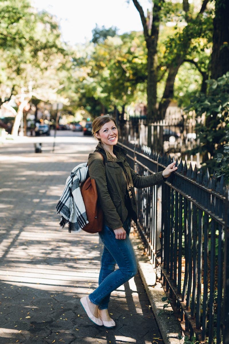 A person walking down a sidewalk next to a fence