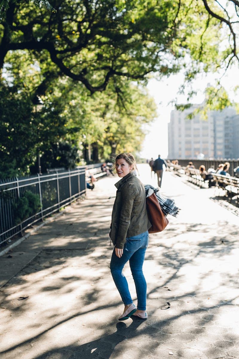 A person walking down a sidewalk next to a tree