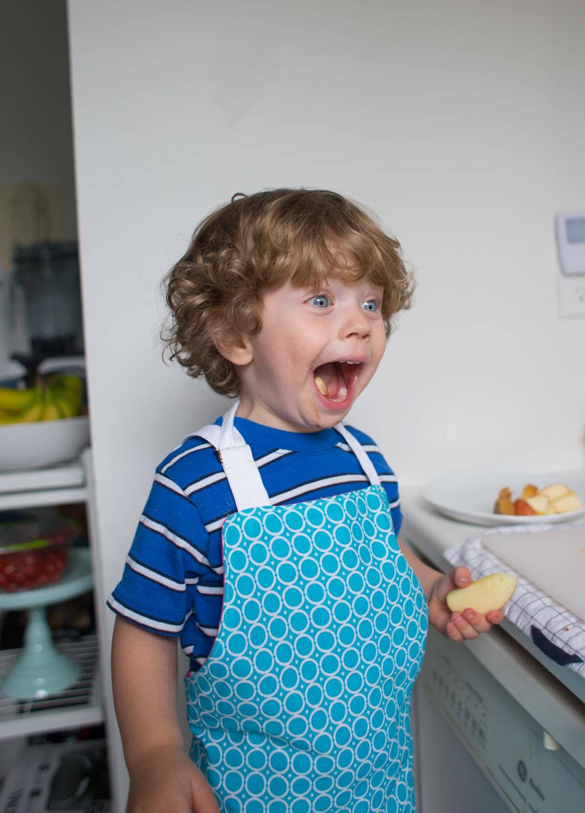 Eddie in an apron holding a slice of an apple