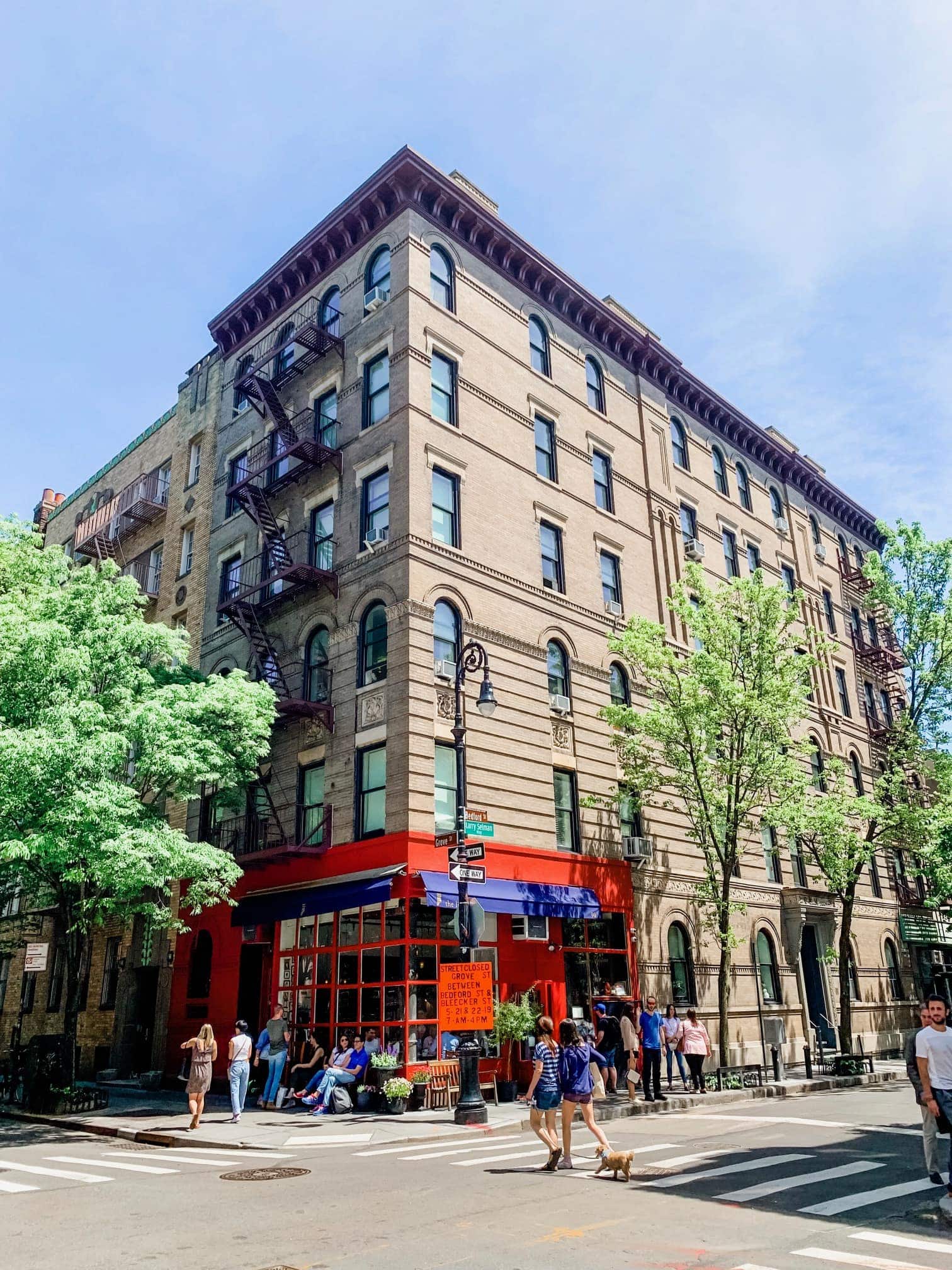 A group of people walking down a street in front of a brick building