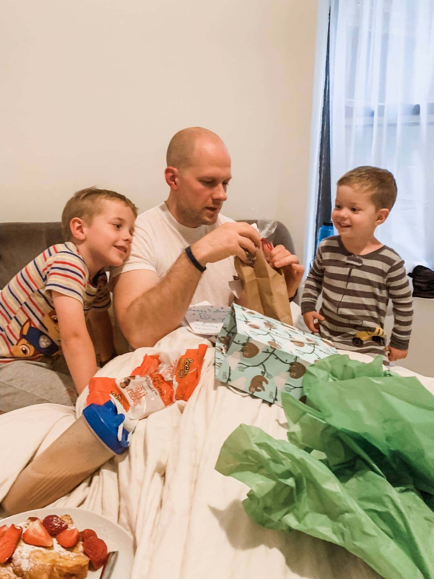 Gordon opening presents in bed with Blake and Eddie beside him
