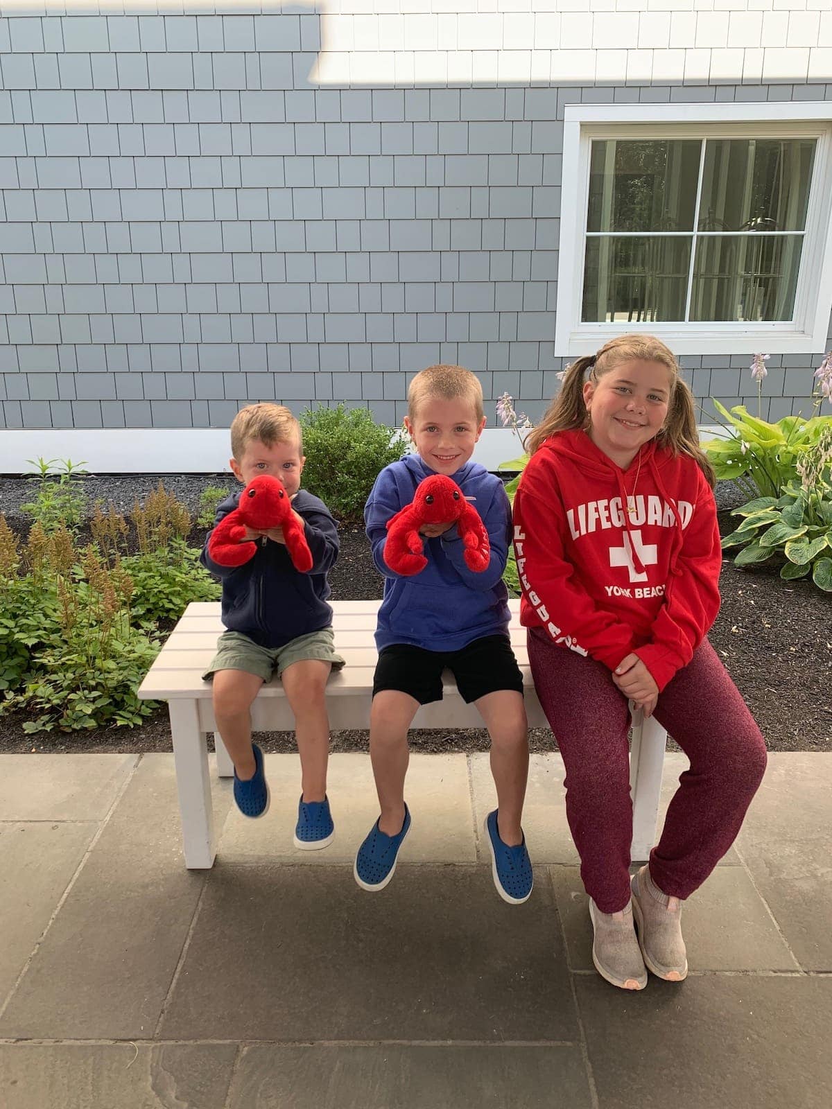 The kids sitting on a bench with lobster plushies