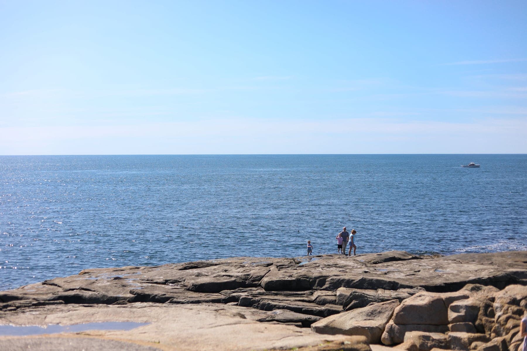 A group of people on a rocky beach next to the ocean