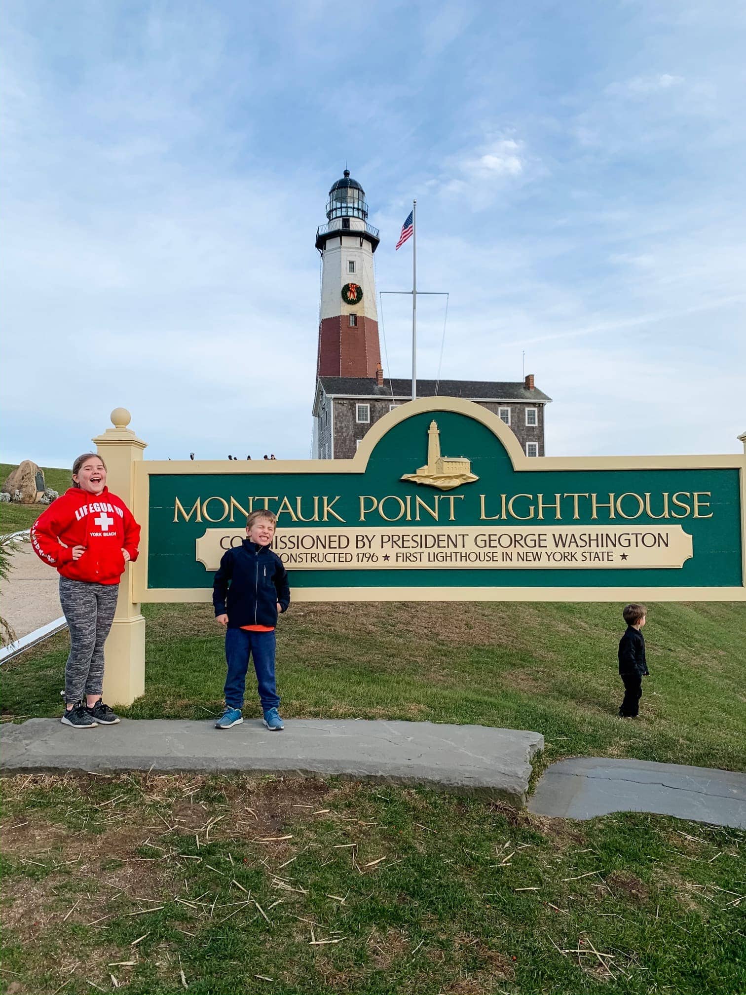Kids standing in front of a lighthouse and sign