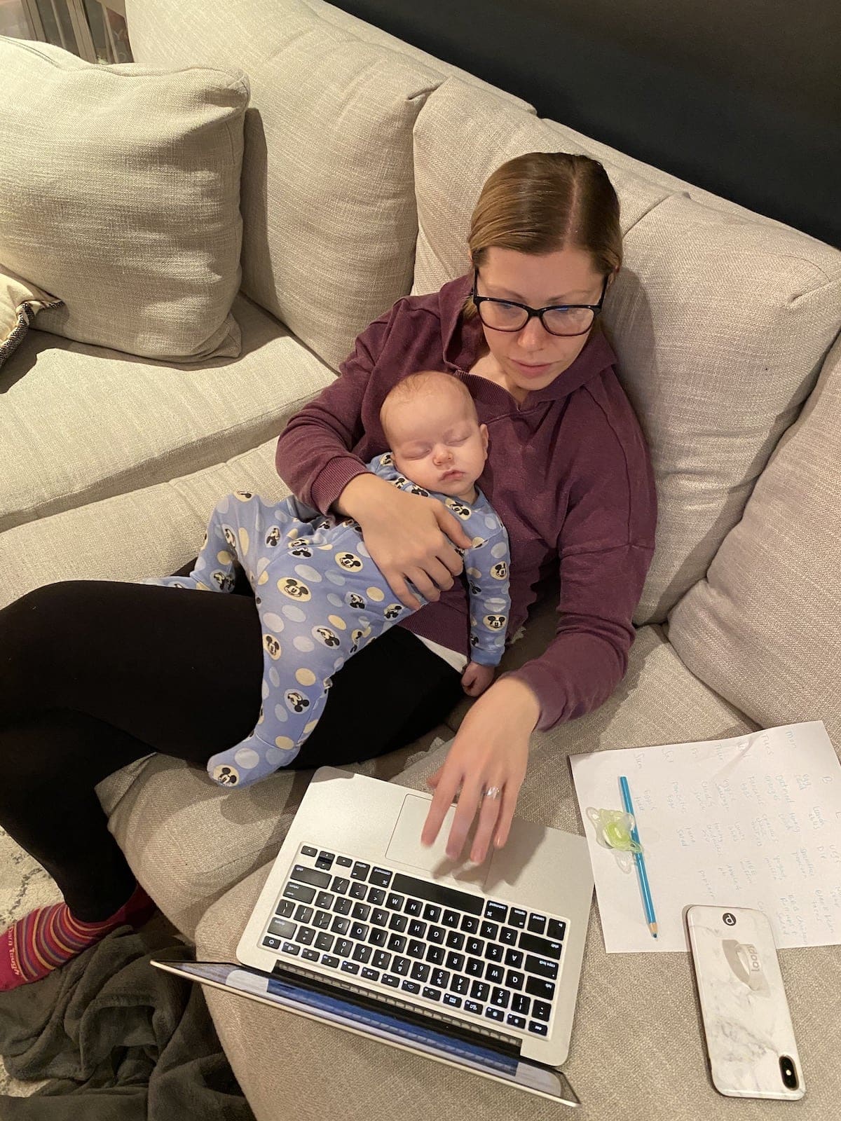 Lauren working on a laptop while holding a sleeping Porter
