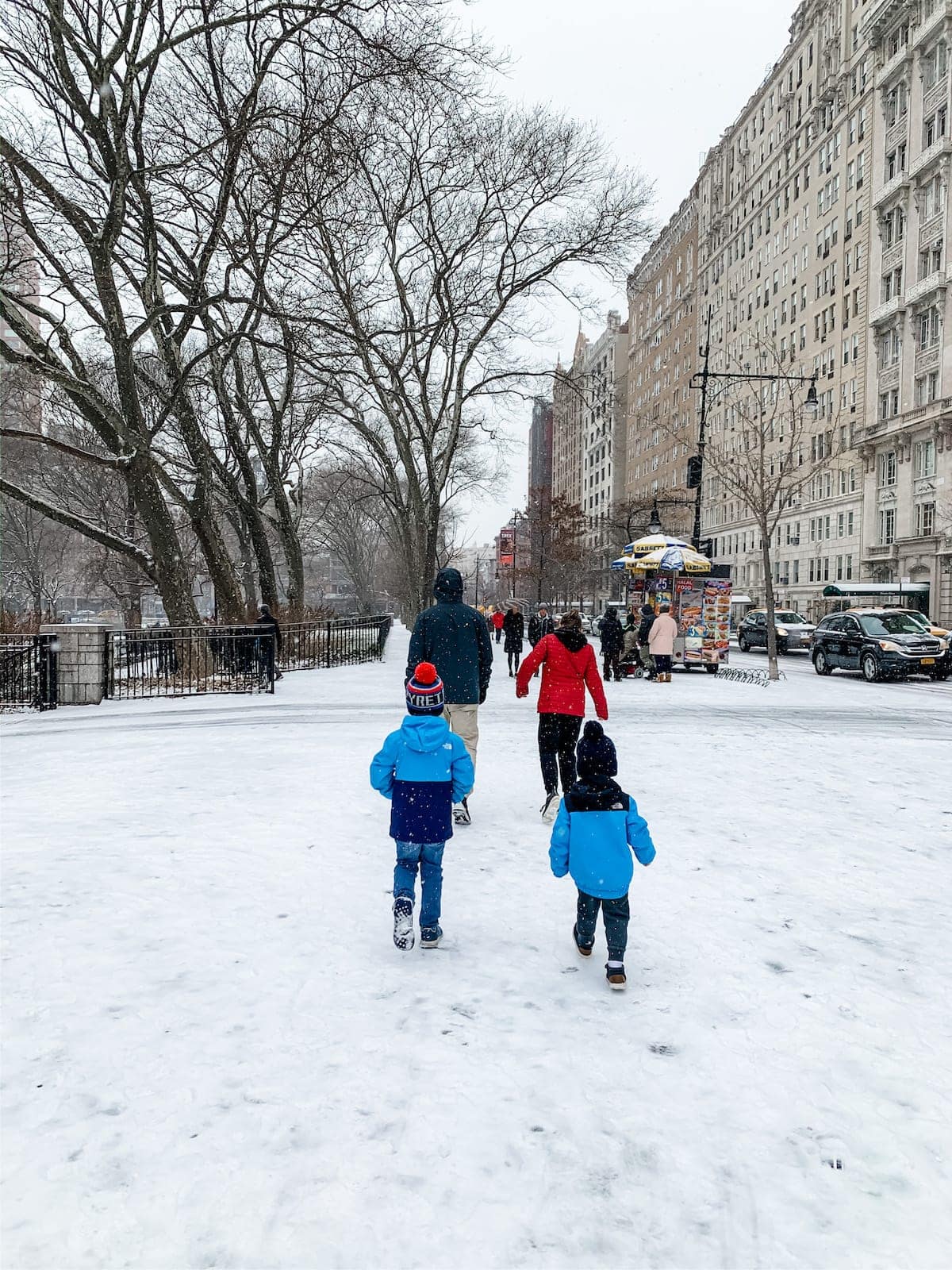 A group of people standing on top of a snow covered sidewalk