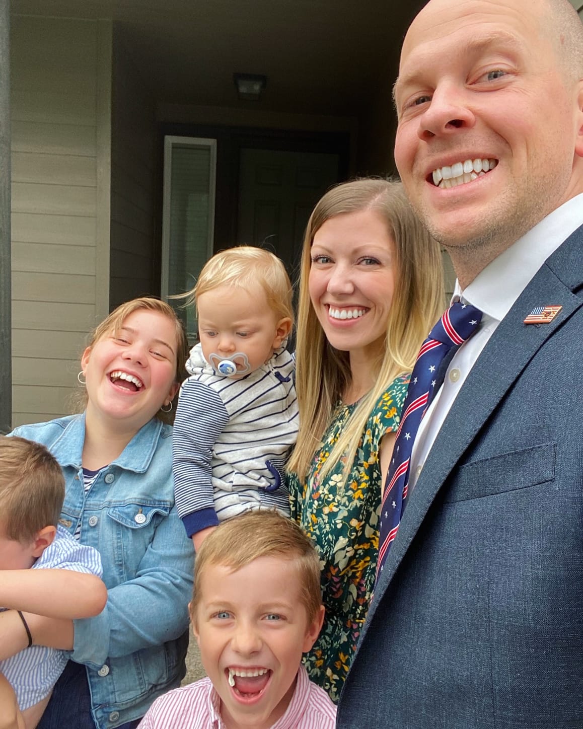 family posing for selfie in front of home