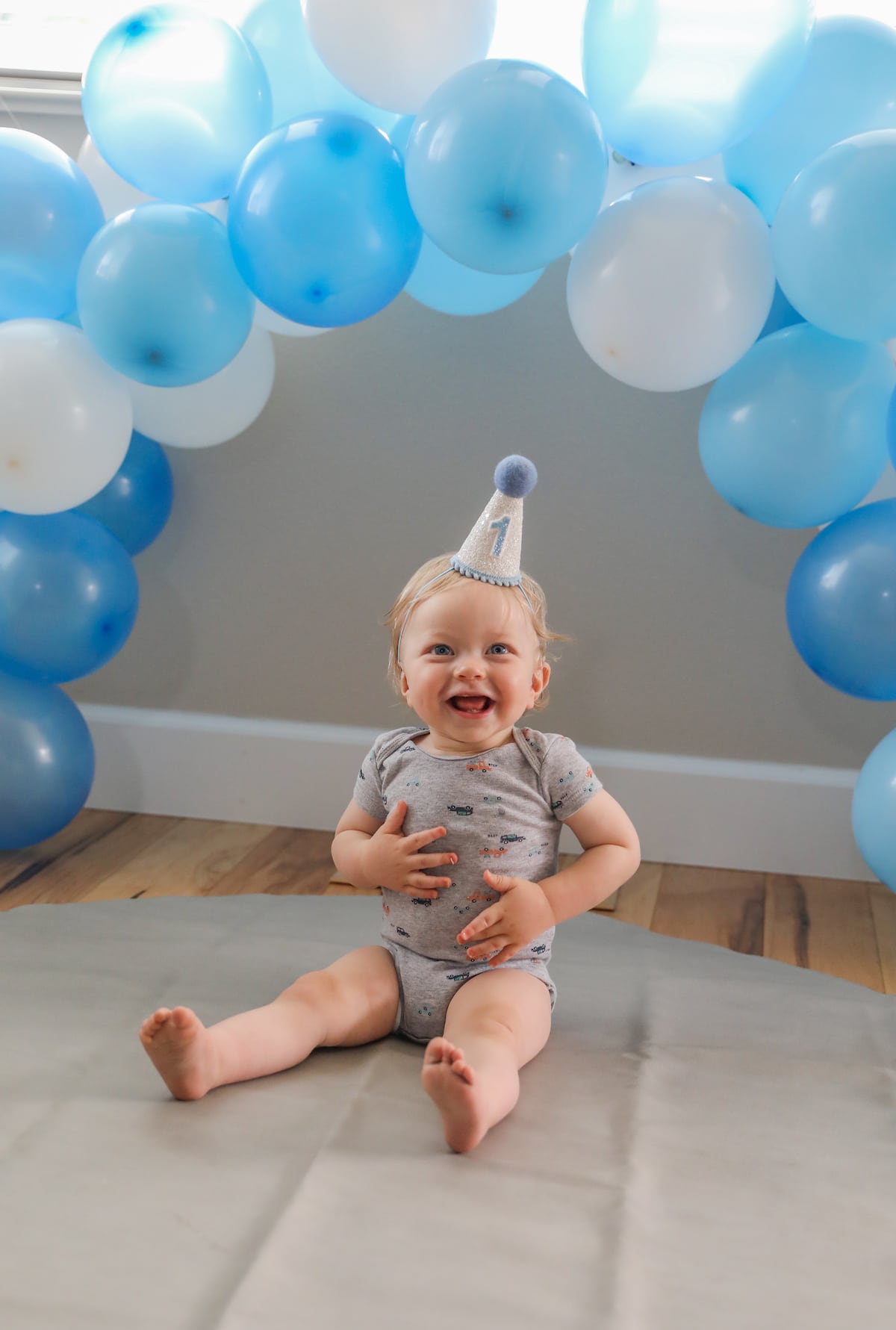 baby smiling under blue balloon arch