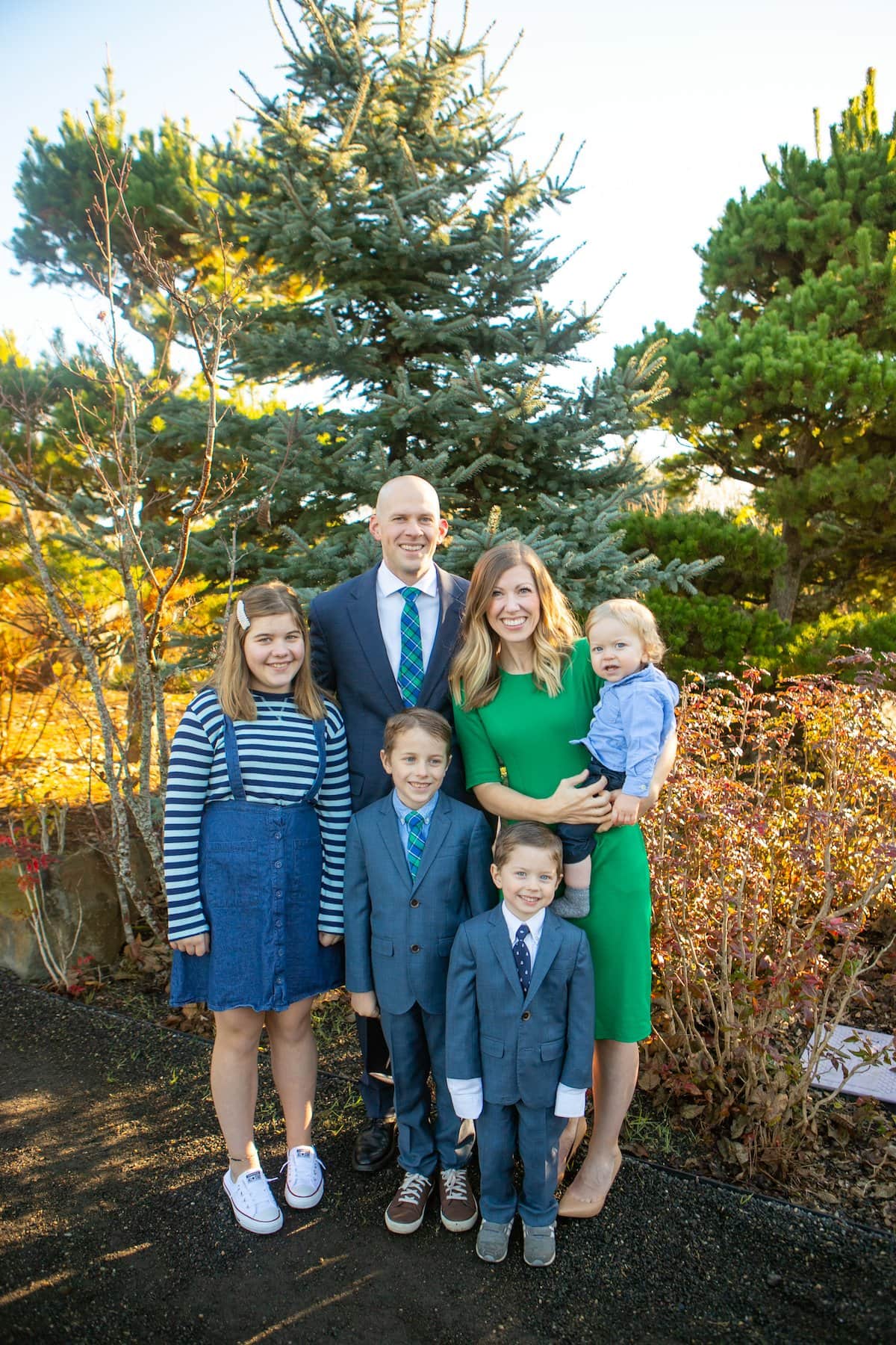 family smiling in front of trees