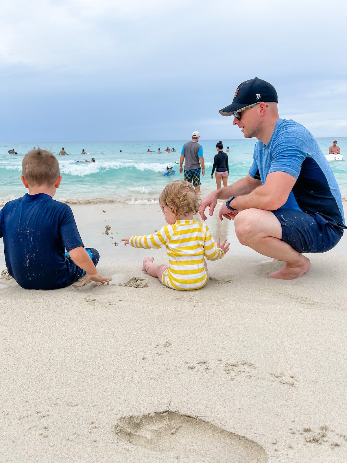 dad with two boys sitting on beach